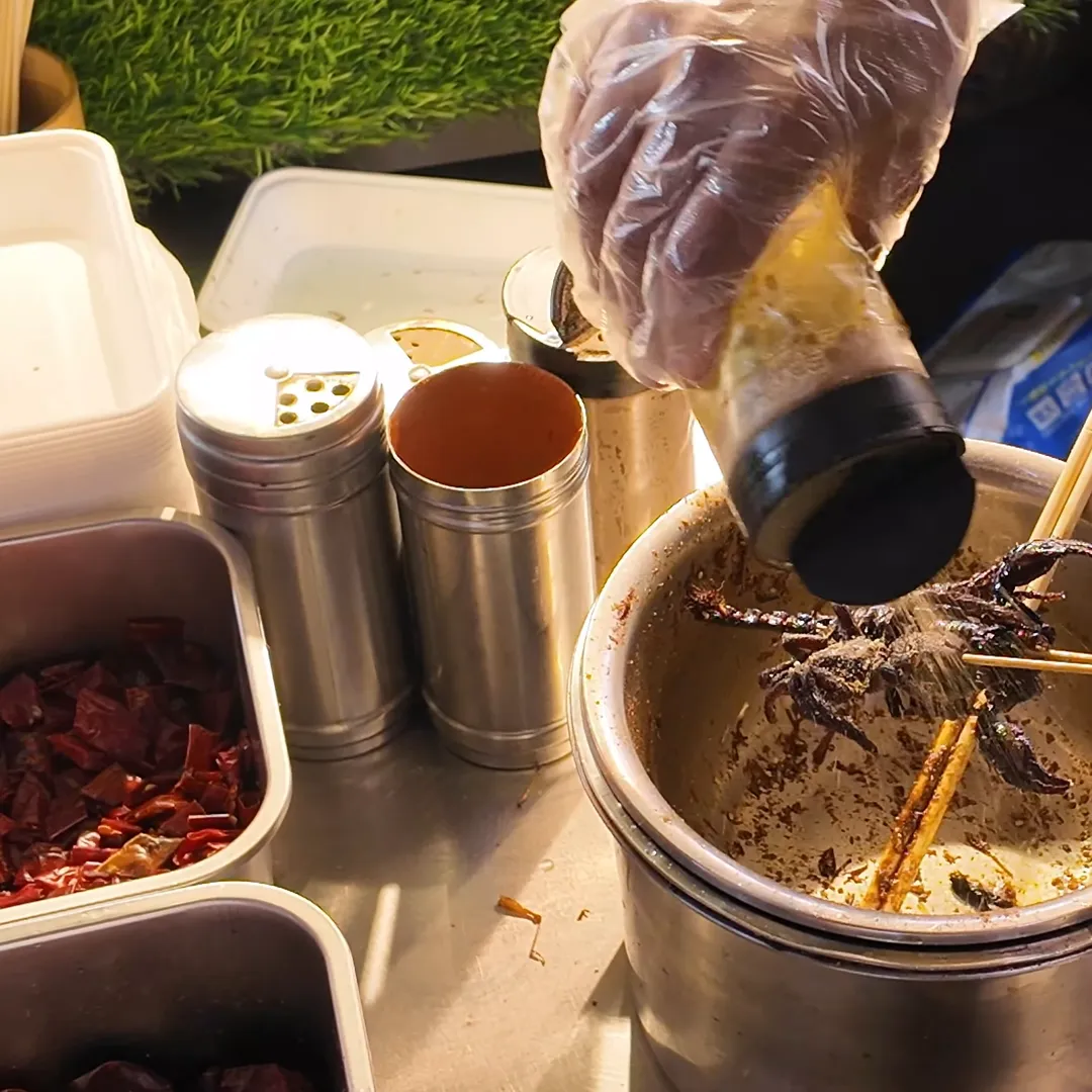 Scorpion skewers being coated in spices