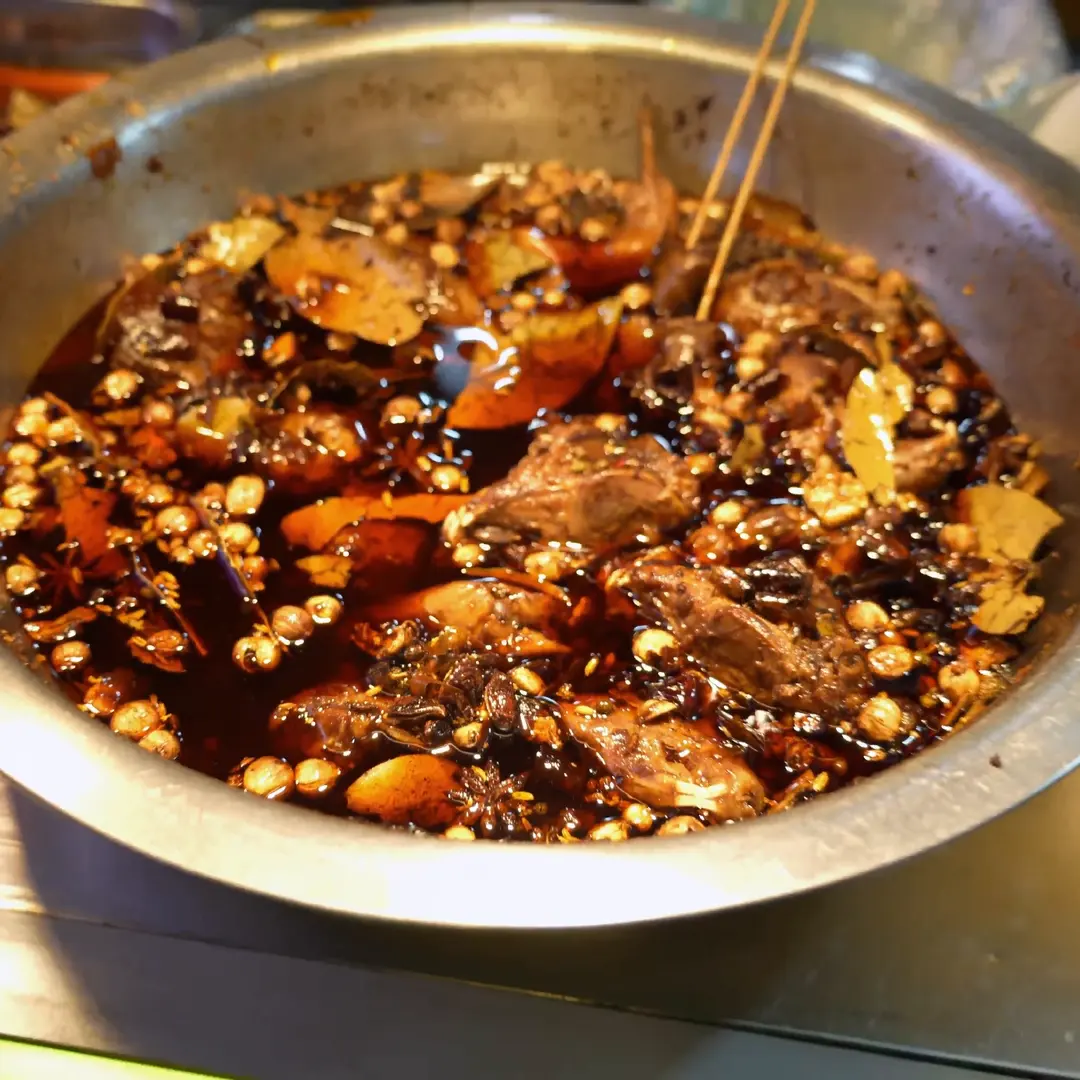 A tub of rabbit heads in braising sauce